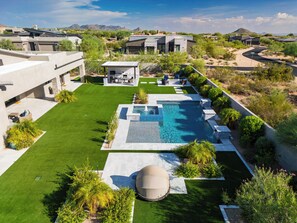 Et moderne resort med swimmingpool, udendørs siddepladser og udsigt over det omkringliggende landskab.