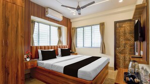 A hotel room with a large bed, wooden wardrobe, ceiling fan, air conditioning unit, and a television on the wall. - Super Collection O Newtown Bus Stand (Barasat)