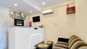 A reception area with a white reception desk, a mounted television, and a wall-mounted air conditioner. - Super Collection O Newtown Bus Stand (Barasat)