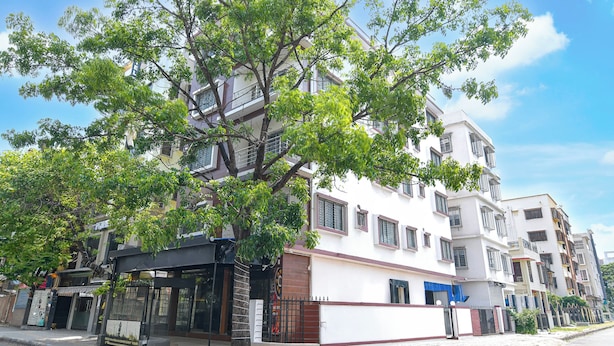 A multi-story building with a white facade, multiple windows, and a tree in front. - Super Collection O Newtown Bus Stand (Barasat)