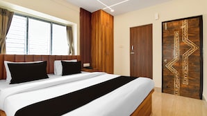 A hotel room with a large bed, a wooden wardrobe, a door with intricate designs, and a window with curtains. - Super Collection O Newtown Bus Stand (Barasat)