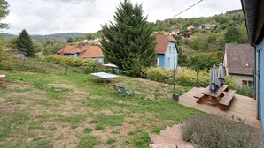 Ett bostadsområde med hus, en gräsyta och en träaltan med ett bord och stolar.