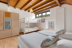 A bedroom with a bunk bed, a wardrobe, a window with a view, and a radiator.