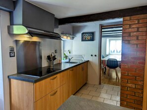 A modern kitchen with wooden cabinets, a stainless steel range hood, and a black countertop.
