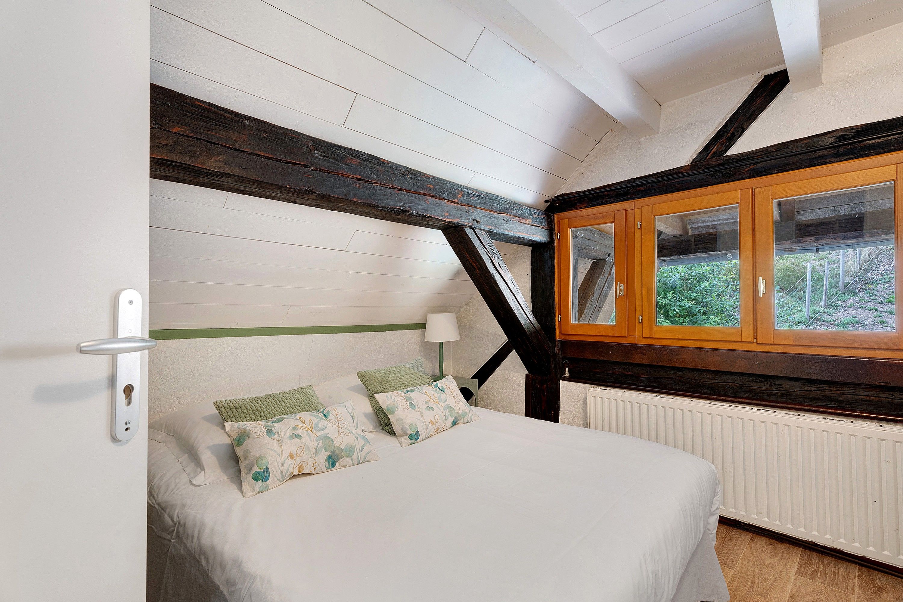 Une chambre à coucher avec un lit, une fenêtre donnant sur un beau paysage et un radiateur.