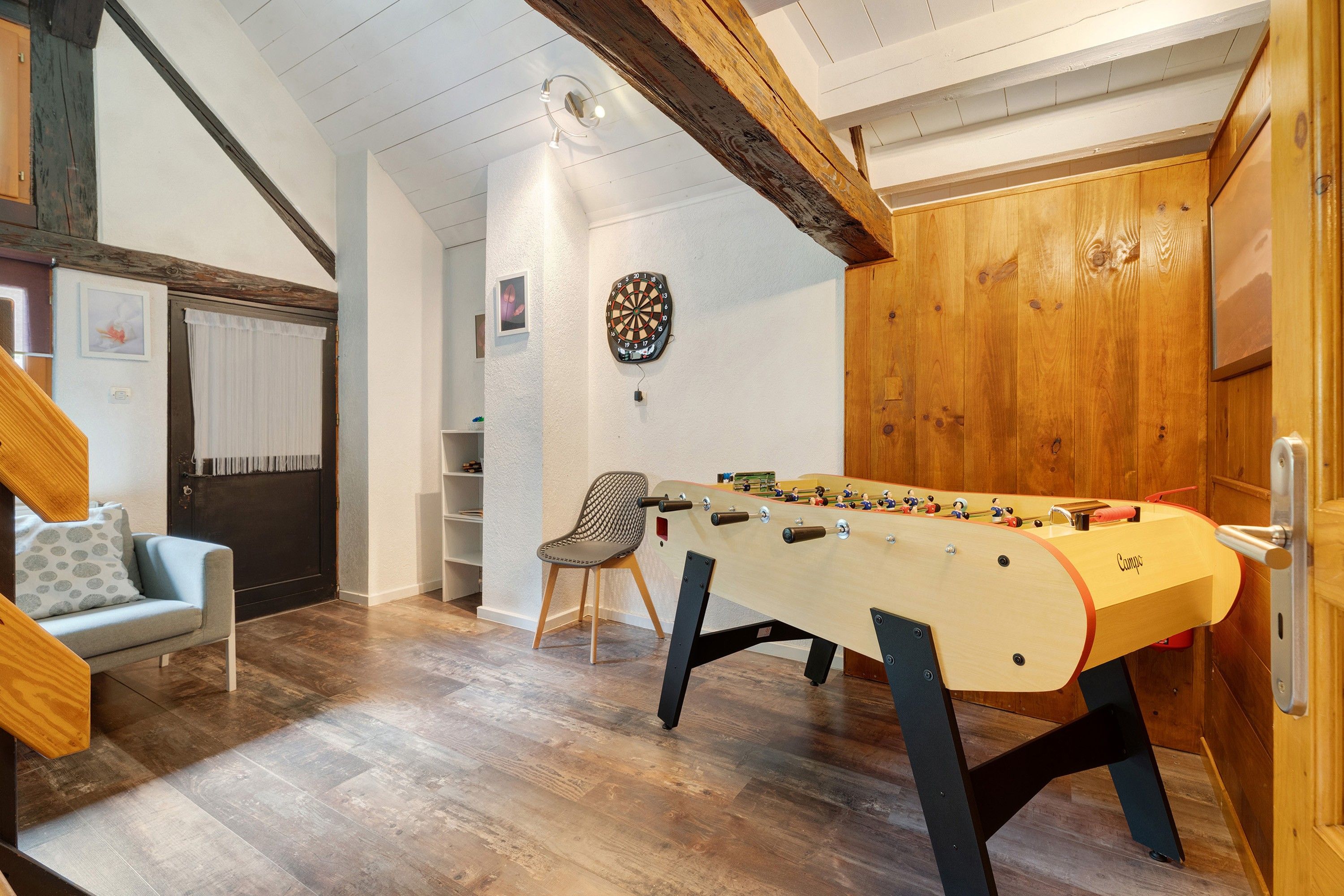 Une pièce avec une table de baby-foot, un jeu de fléchettes et un canapé.