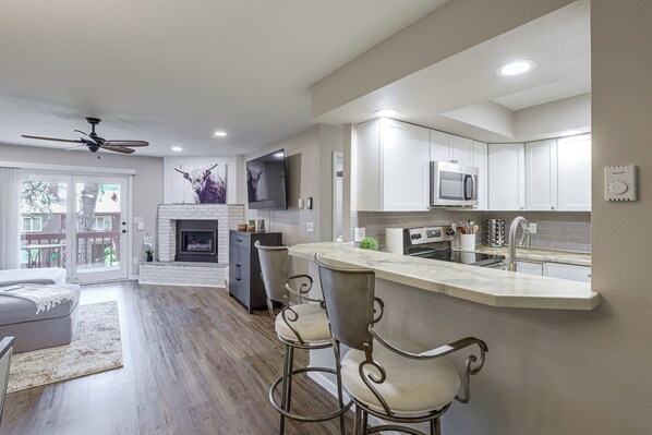 A modern kitchen with a bar area, a fireplace, and a dining area with a view. - Tasteful Townhome Near Black Hills National Forest (Rapid City)