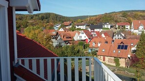 Ein Wohngebiet mit Häusern, einem Balkon und einer hügeligen Landschaft im Hintergrund.