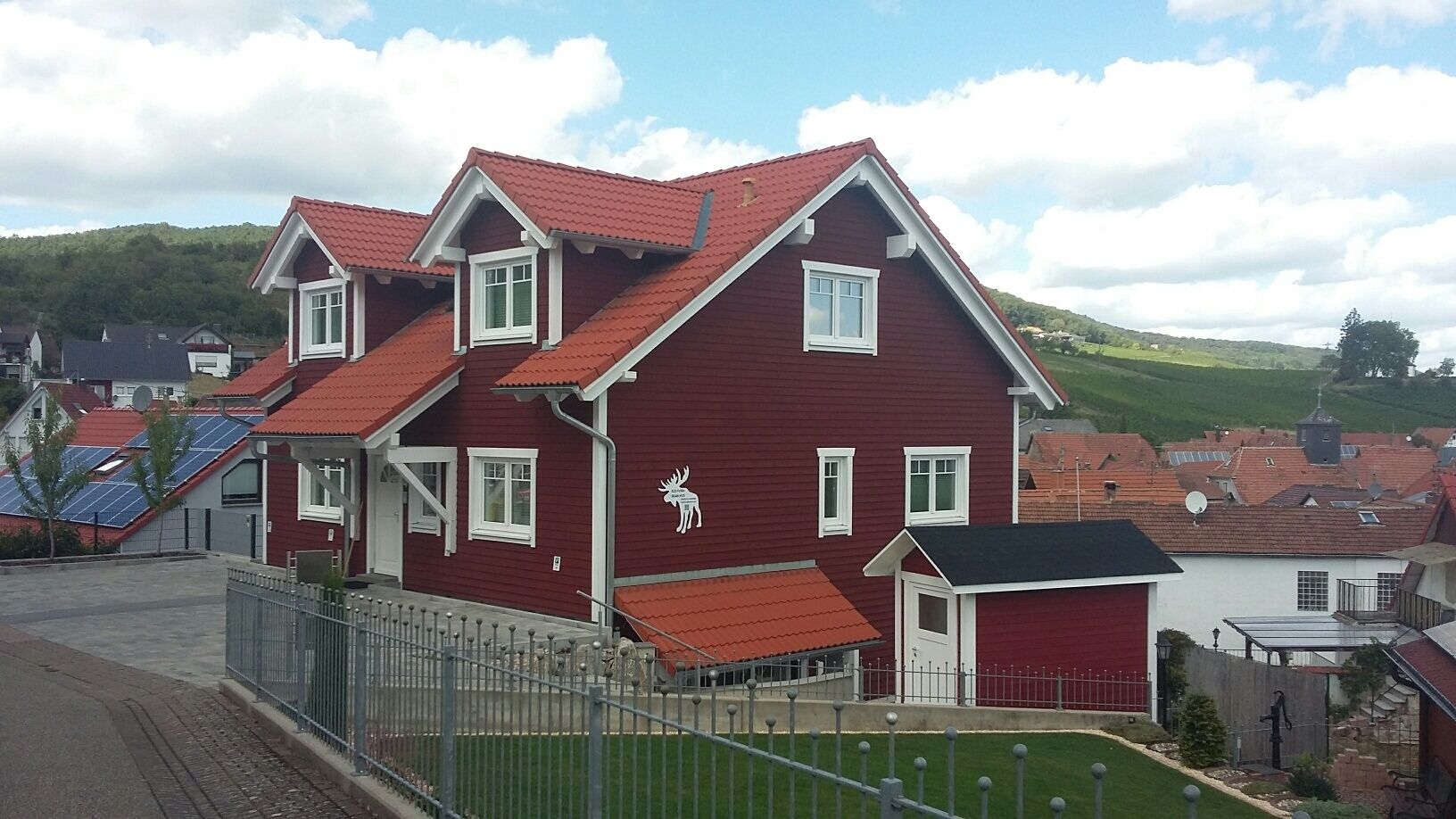 Ein zweistöckiges Haus mit roter Fassade und weißem Fensterrahmen.