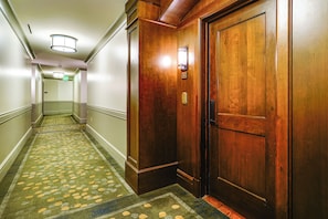 Ein Hotelkorridor mit Teppichboden, Holztüren und einer Deckenleuchte.