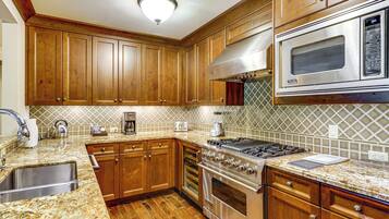 Cocina con gabinetes de madera, estufa de acero inoxidable y microondas.