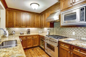 A kitchen with wooden cabinets, a stainless steel range, and a microwave.