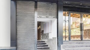 Una escalera conduce a una entrada con puerta de cristal y barandilla de metal.