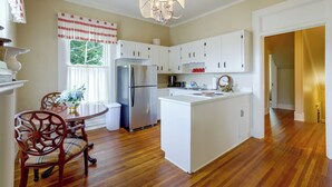A kitchen with a central island, white cabinetry, a stainless steel refrigerator, and a chandelier.