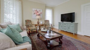 A living room with a sofa, chairs, a coffee table, a television, and a cabinet.