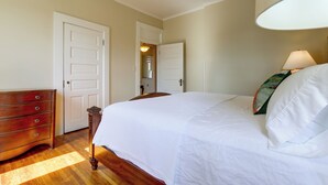 A bedroom with a bed, dresser, and two doors leading to other rooms.