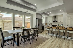 A modern kitchen with a dining area, large windows, and a view of the backyard. - Walk to Main St Tomball! Family Retreat w/ Yard (Tomball)