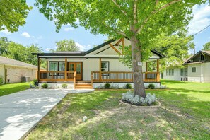 A single-story house with a front porch, a tree in the yard, and a clear sky.