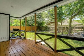 A wooden deck with a view of a backyard, a barbecue grill, and a fenced area.