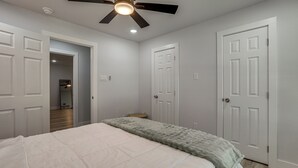 Ein Schlafzimmer mit Bett, Deckenventilator und weißen Türen.