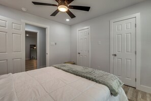 A bedroom with a bed, a ceiling fan, and white doors. - Walk to Main St Tomball! Family Retreat w/ Yard (Tomball)
