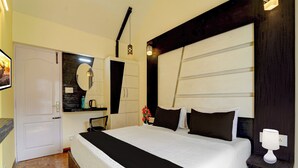 A hotel room with a large bed, a bedside table, a nightstand, a mirror, a wardrobe, and a door. - Super Collection O Hill View Point (Kodaikanal)