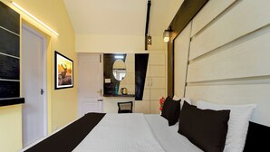 A hotel room with a large bed, a mirror, a framed picture on the wall, and a small table with a kettle. - Super Collection O Hill View Point (Kodaikanal)