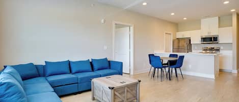 Una sala de estar moderna con un sofá modular, una mesa de centro y un comedor con sillas.