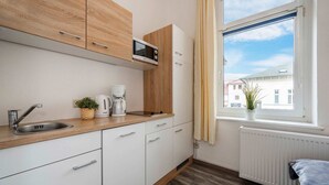 Moderni keittiö, jossa on mikroaaltouuni, kahvinkeitin ja pesuallas.
