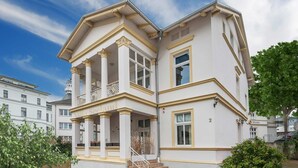 Un edificio bianco con un balcone e una scala che conduce all'ingresso.