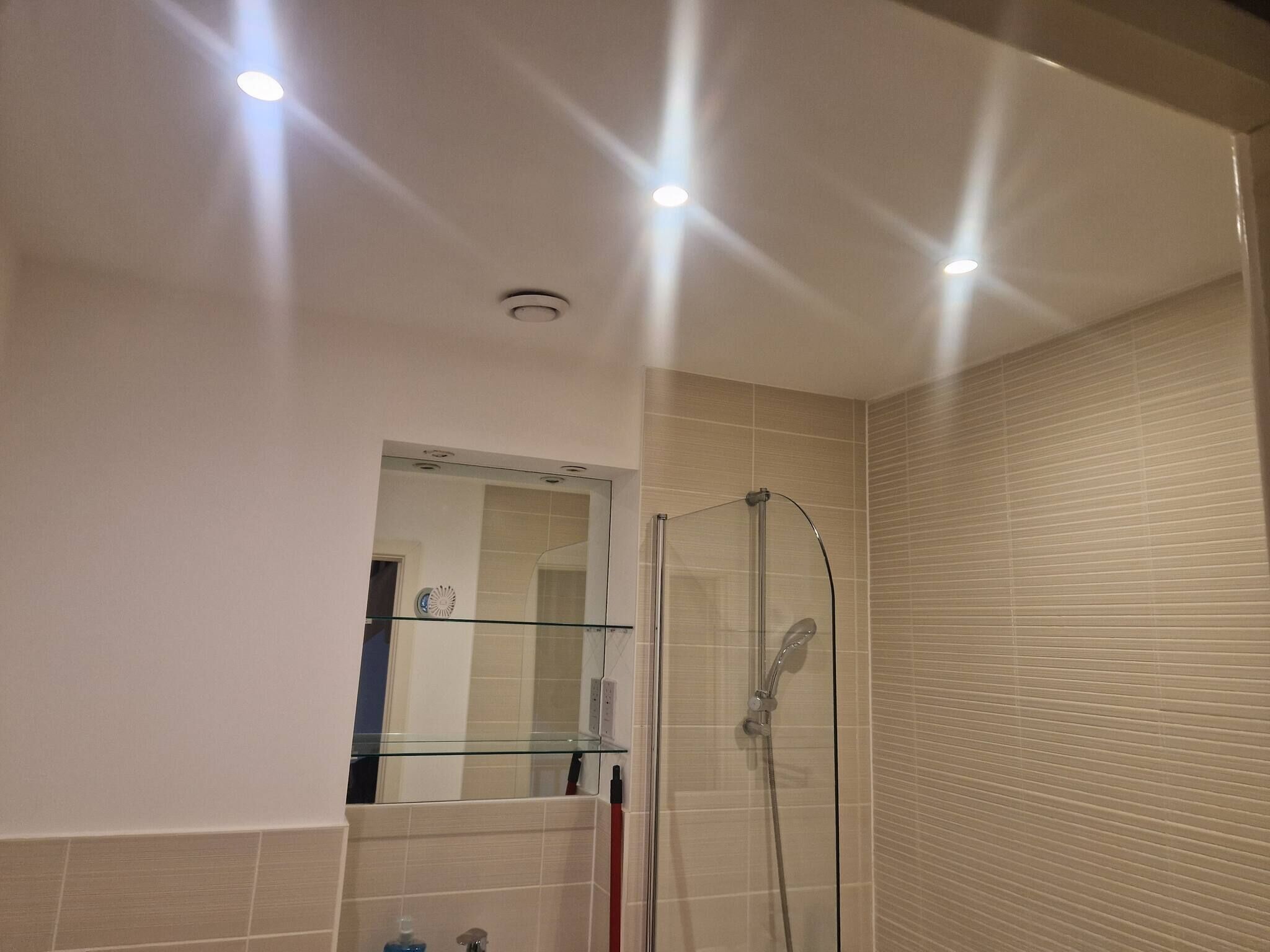A modern bathroom with a glass shower enclosure, a mirror, and recessed ceiling lights.