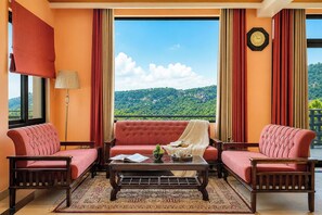 Una habitación con un conjunto de sofá, una mesa de centro y vista a un paisaje verde.