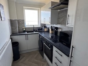 A compact kitchen with a built-in oven, microwave, and a window for natural light. - Stunning Sea View Flat on The Leas – Panoramic Estuary Sunsets, Steps to Beach (Minster on Sea)