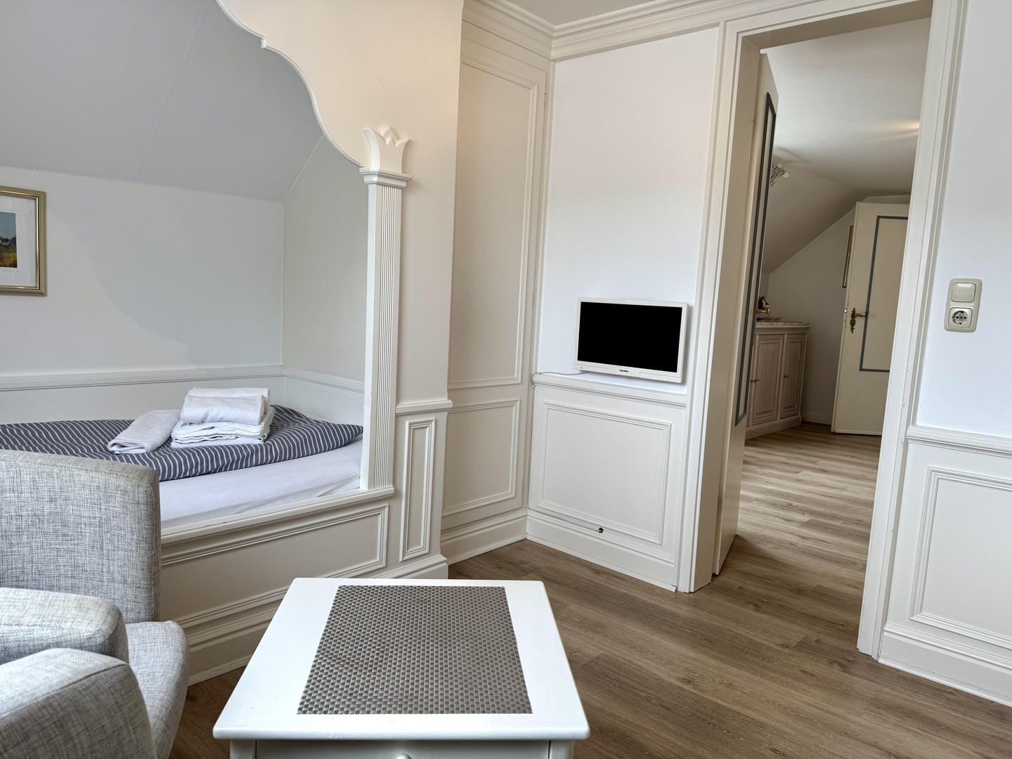 A hotel room with a bed, a TV, a small table, and a chair.