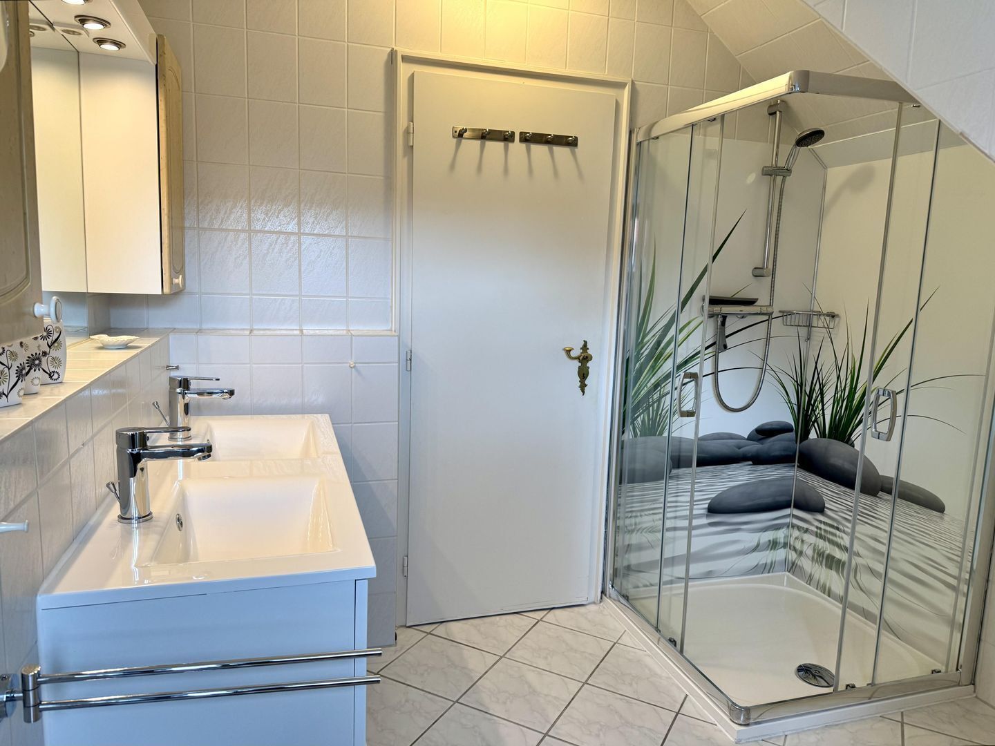 Un baño moderno con cabina de ducha de vidrio, un lavabo blanco y una puerta con manija.