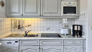 A kitchen with white cabinetry, a Siemens dishwasher, a microwave, and a coffee maker. - Kampstraße, Apartment 3a - Cozy 3-room vacation apartment with a balcony in a quiet (Sylt)