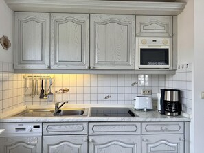 A kitchen with white cabinetry, a Siemens dishwasher, a microwave, and a coffee maker. - Kampstraße, Apartment 3a - Cozy 3-room vacation apartment with a balcony in a quiet (Sylt)