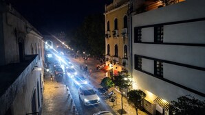 Une scène de rue nocturne avec des bâtiments, des véhicules et des piétons.