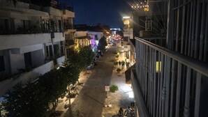Une vue nocturne d’une rue, avec des bâtiments, une chaussée et quelques piétons.