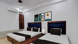 A hotel room with two beds, a wooden headboard, a nightstand, a lamp, and artwork on the wall. - Collection O Shri Khatu Shyam Ji Temple (Danta Ramgarh)