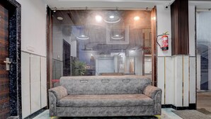 A modern interior with a grey sofa, a glass partition, and a fire extinguisher on the wall. - Collection O Shri Khatu Shyam Ji Temple (Danta Ramgarh)