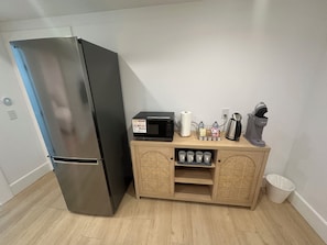 A compact kitchen with a stainless steel refrigerator, a microwave, a coffee maker, and a small wooden cabinet with storage. - Cozy Burnaby Heights Suite Private 1BR + 1 Bath (Burnaby)