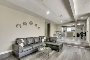 A modern living room with a sectional sofa, a coffee table, and decorative wall art. - 6BR House w/ Massive Parking, Centrally Located (Houston)