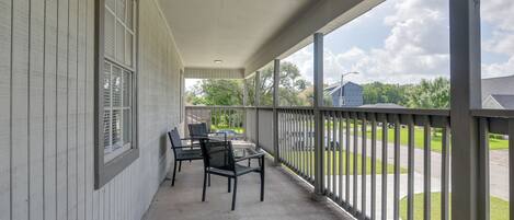 Une véranda abritée avec une table et des chaises, une vue sur la rue et un bâtiment en arrière-plan.