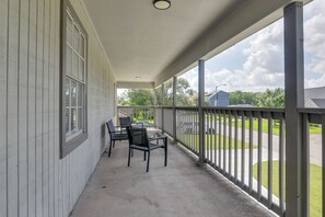 Eine überdachte Veranda mit Tisch und Stühlen, Blick auf die Straße und ein Gebäude im Hintergrund.