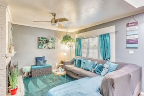 A living room with a sofa, a coffee table, a hanging plant, and a ceiling fan.