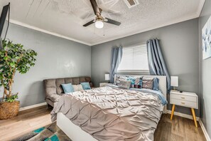 A bedroom with a bed, a nightstand, a lamp, a ceiling fan, and a window with curtains. - Gateway to East Bay! Inviting Apartment (Bay Point)