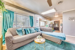 A modern living room with a sectional sofa, a round coffee table, and a teal rug.