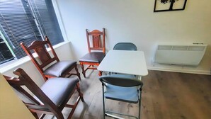 A dining area with a table, chairs, a radiator, and a window with blinds. - Joydens Wood, 2-bed Apt, Sleeps 4 With Parking (Grays)