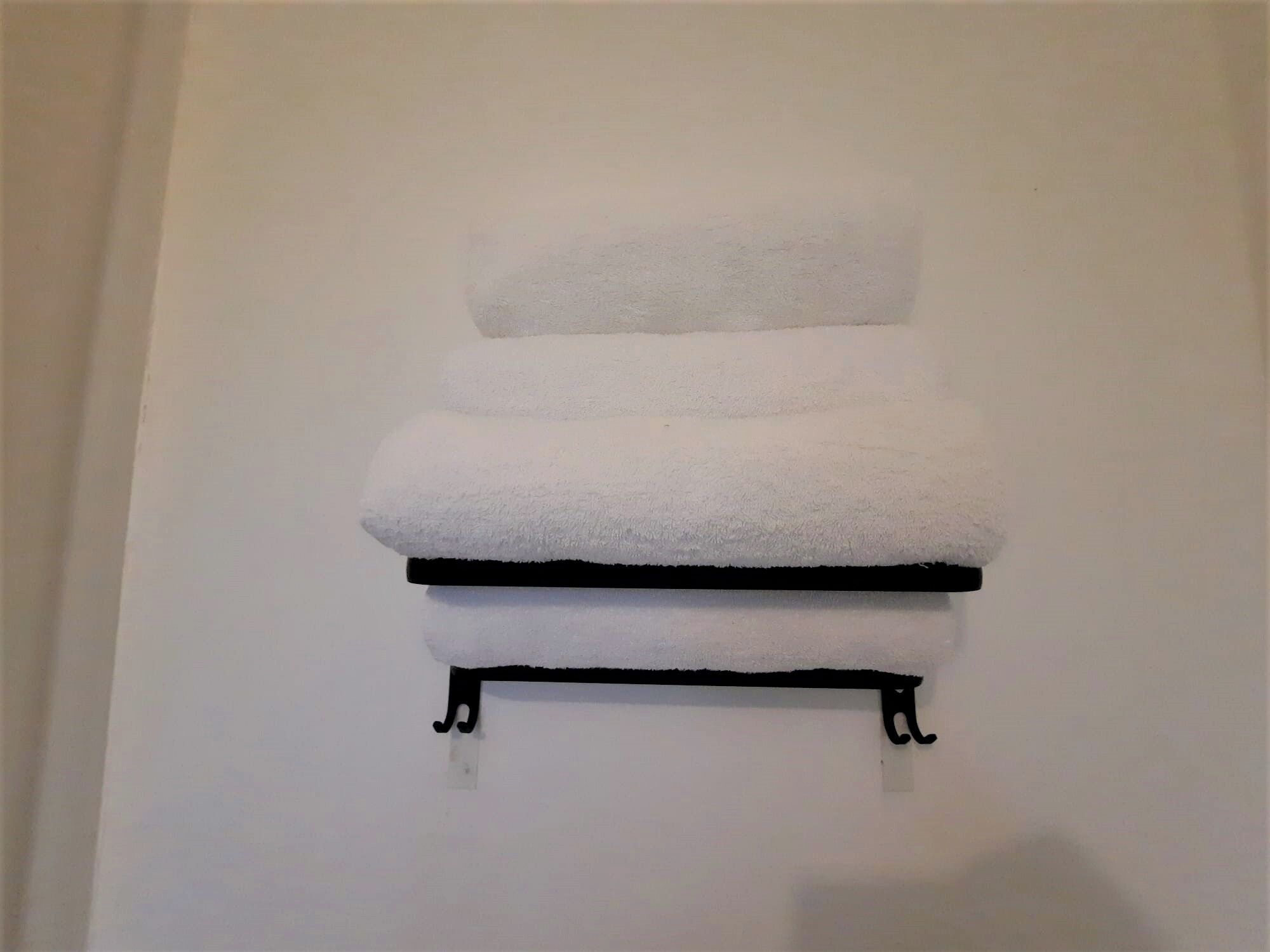 Un mur blanc sur lequel se trouve un objet noir qui ressemble à un lit ou à un canapé.